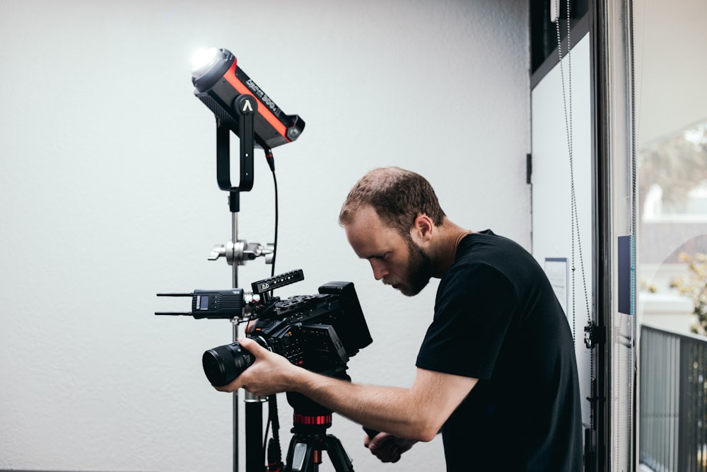 man in black crew neck t-shirt holding black and red camera