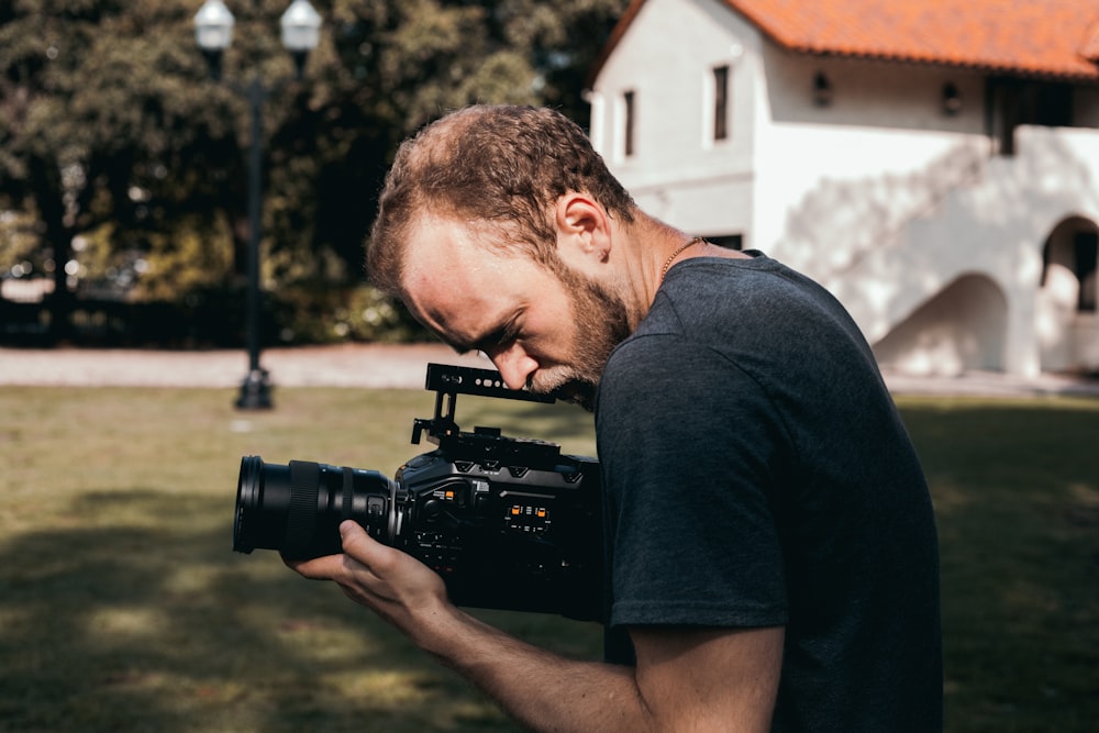 man in black crew neck t-shirt holding black dslr camera