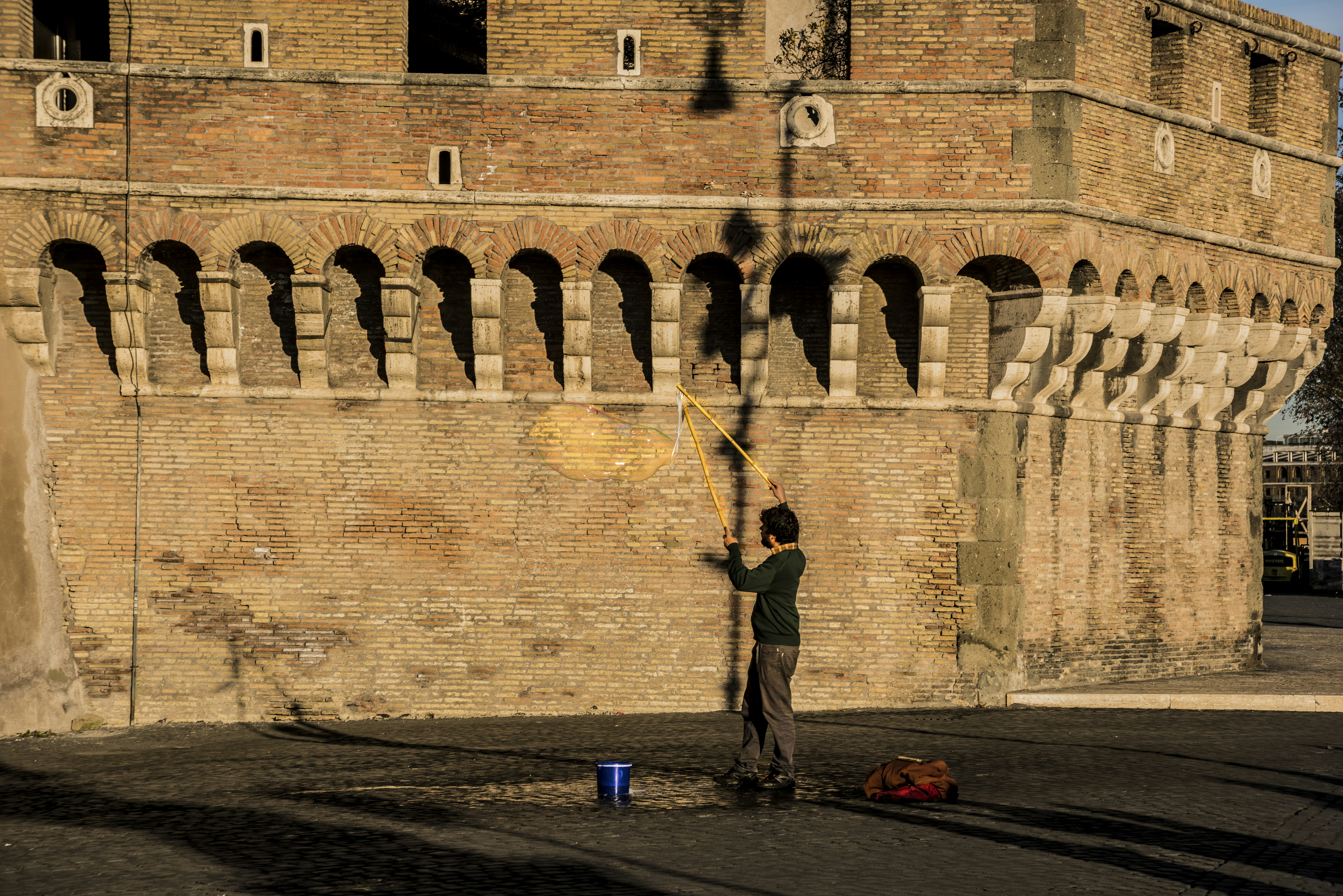 man in black jacket and pants standing beside brown concrete wall during daytime