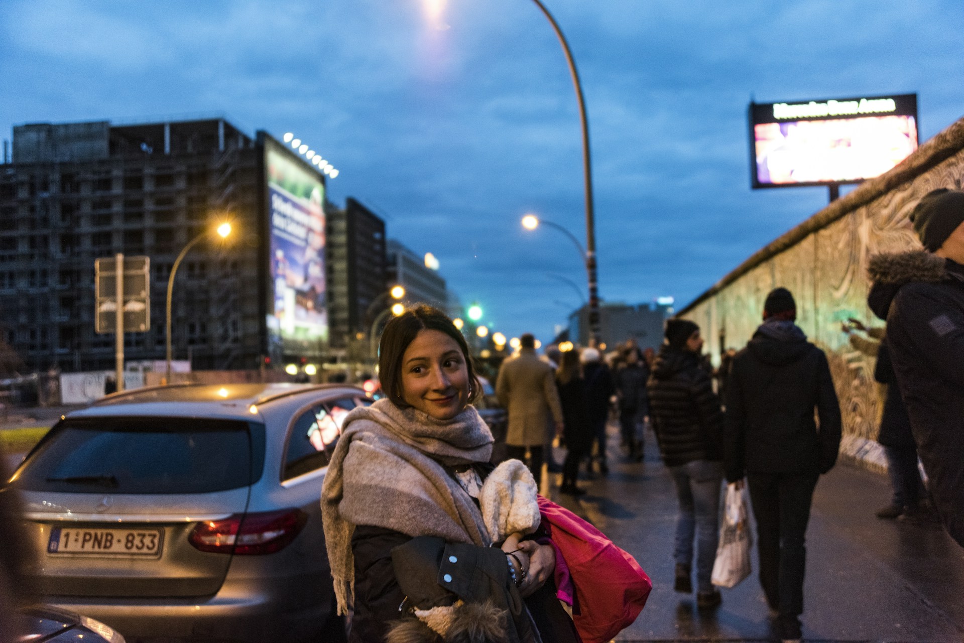 woman in brown coat standing near white car during night time
