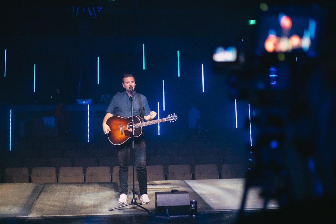 man in black pants playing guitar on stage