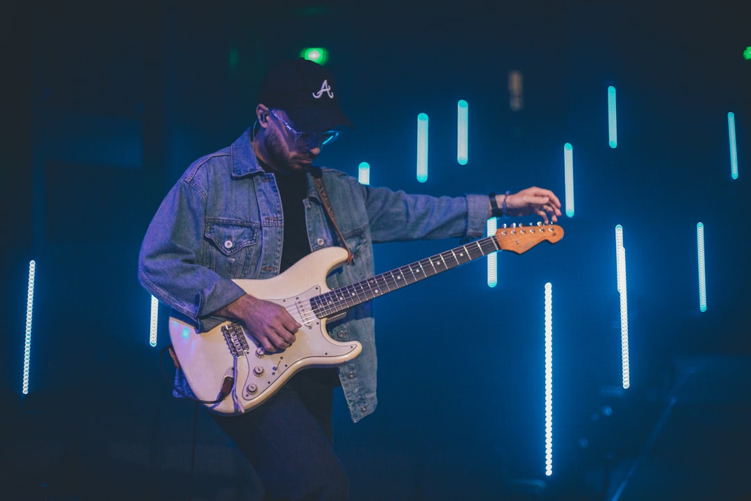 man in blue denim jacket playing electric guitar