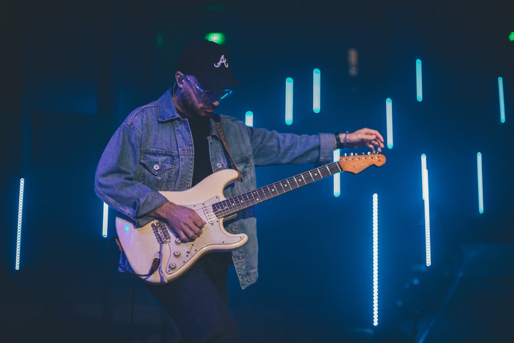 man in blue denim jacket playing electric guitar