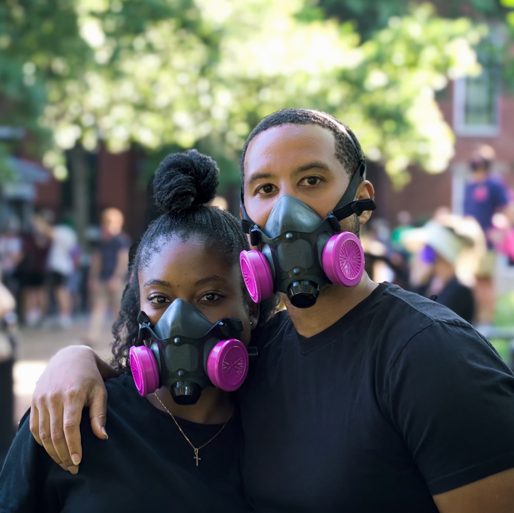 homme en t-shirt à col rond noir portant un masque à gaz violet et vert