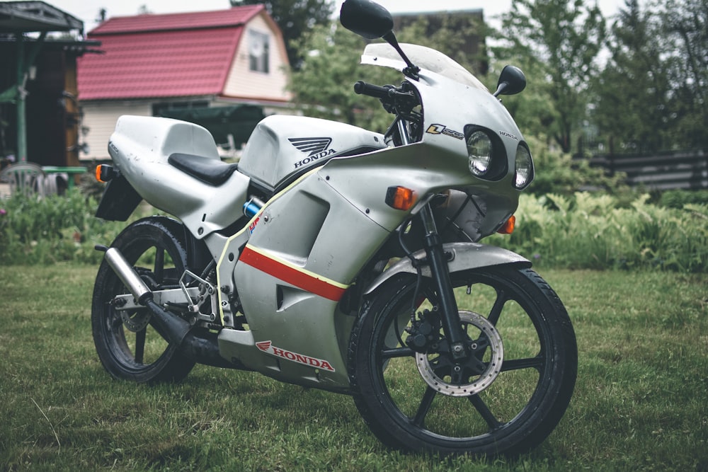 white and red honda sports bike parked on green grass field during daytime