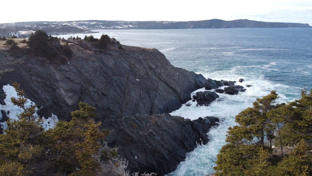 black rock formation on body of water during daytime