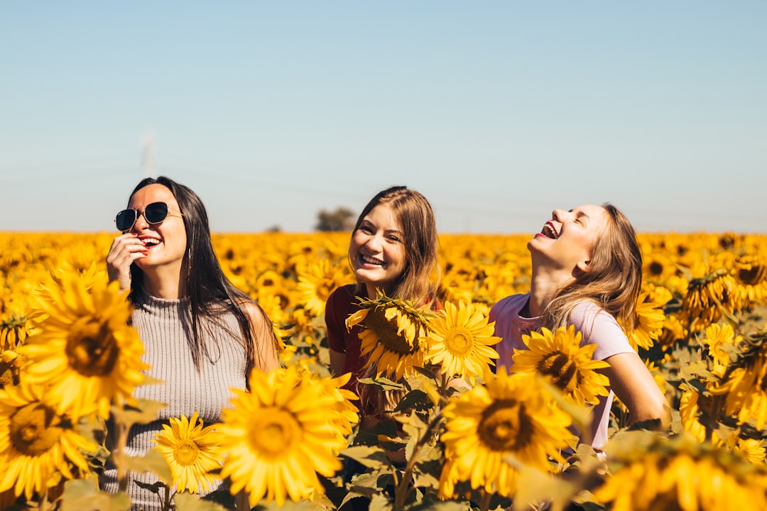 Three young women in sunflower field laughing