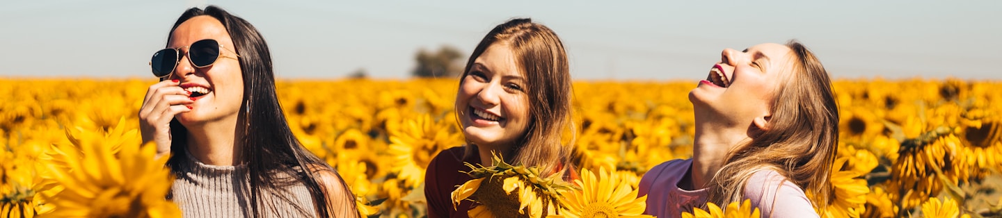 woman in white and black striped shirt standing on yellow sunflower field during daytime