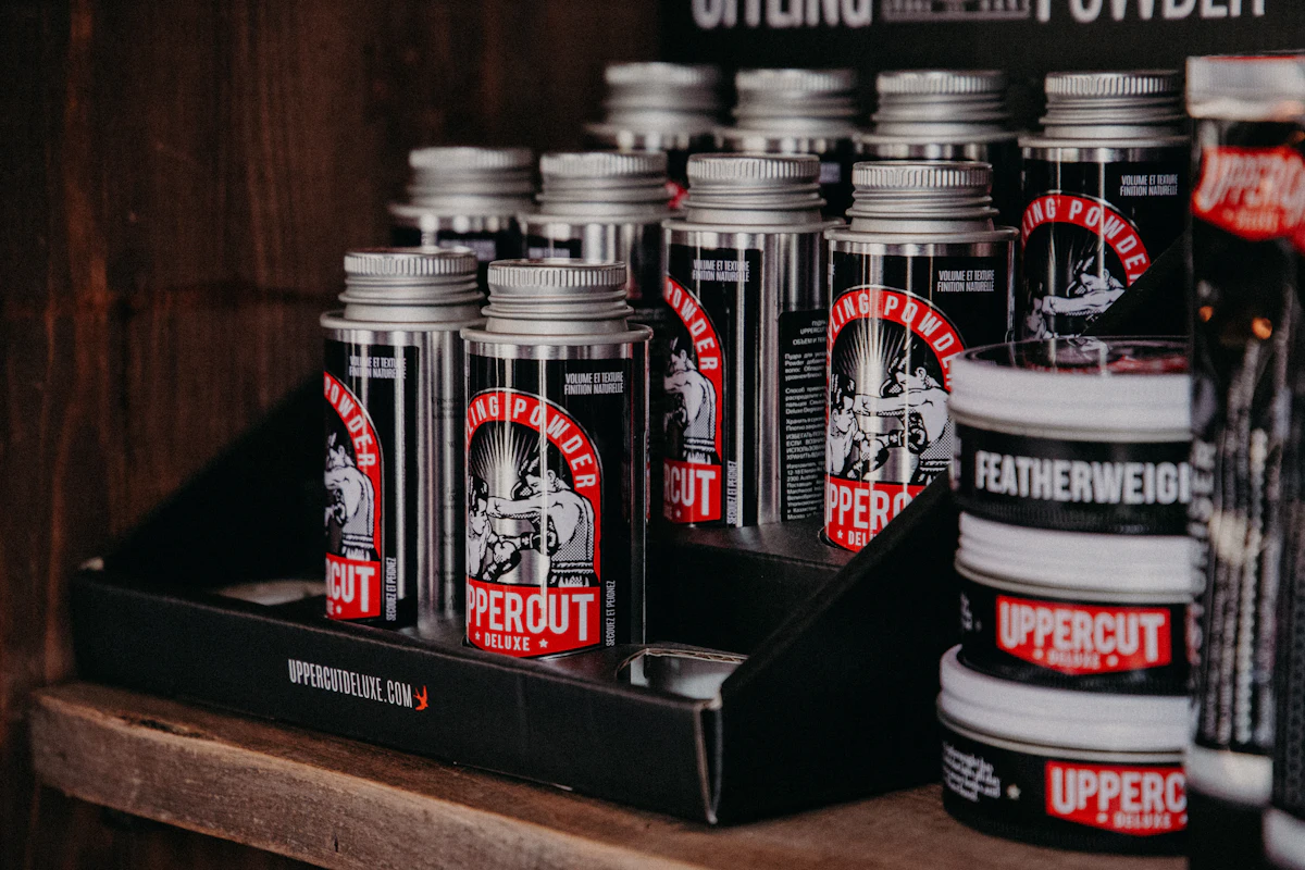 Shelf of matte clay, pomade tins and beard oil on the shop backbar