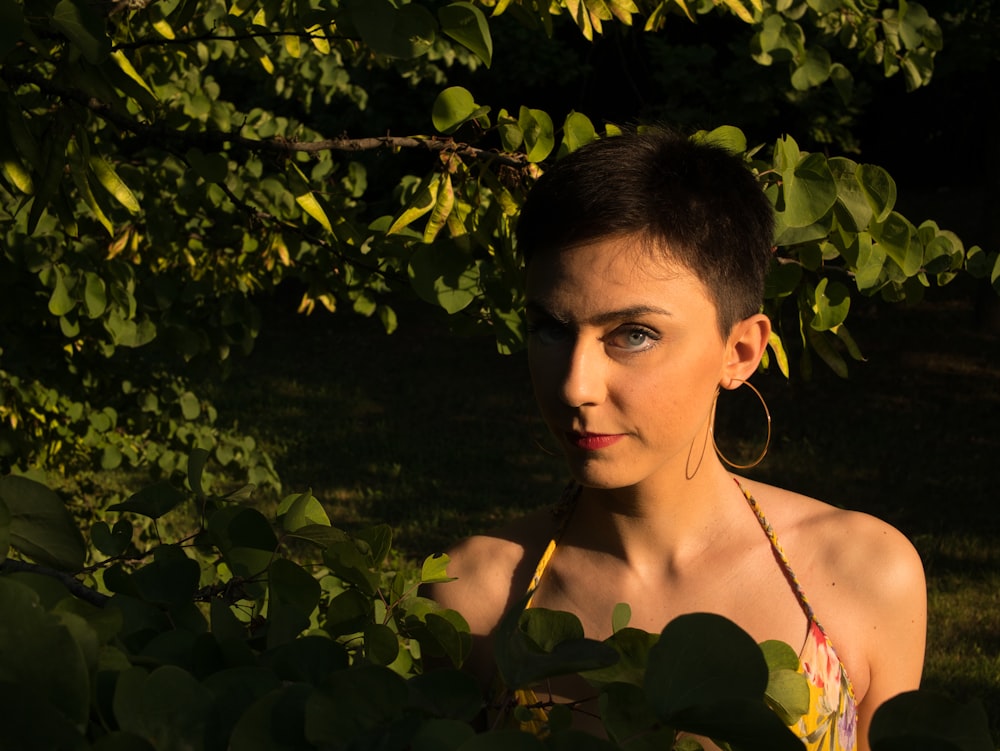 woman in black spaghetti strap top standing beside green leaves