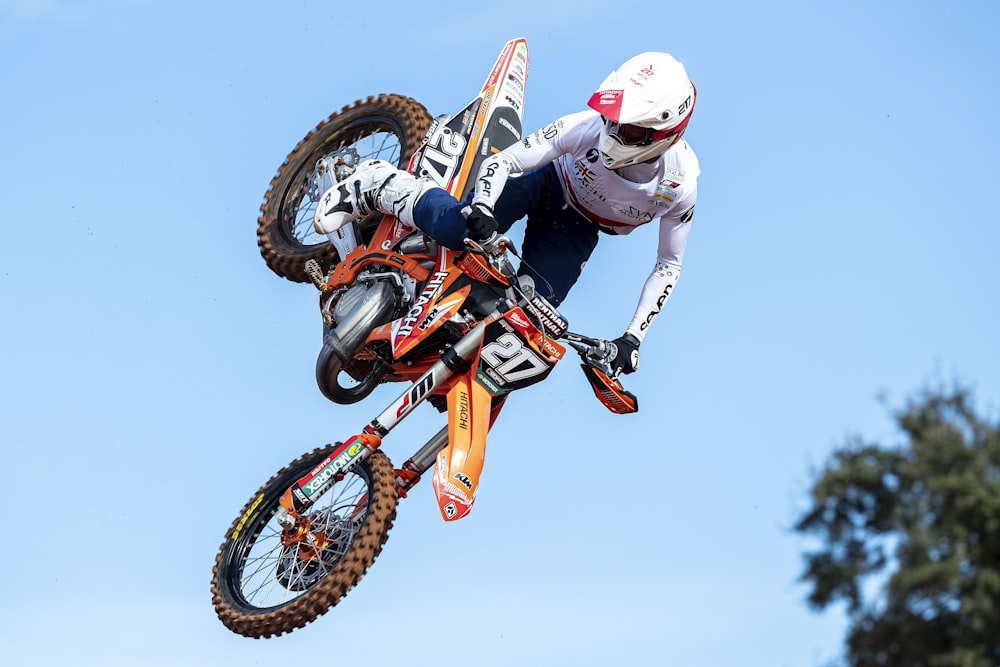 man in white and orange motocross suit riding motocross dirt bike