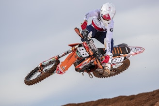 man in red and white motocross helmet riding motocross dirt bike