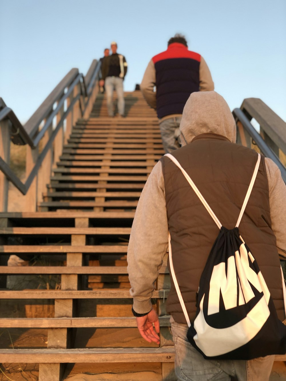 man in brown jacket and red knit cap walking on wooden bridge during daytime