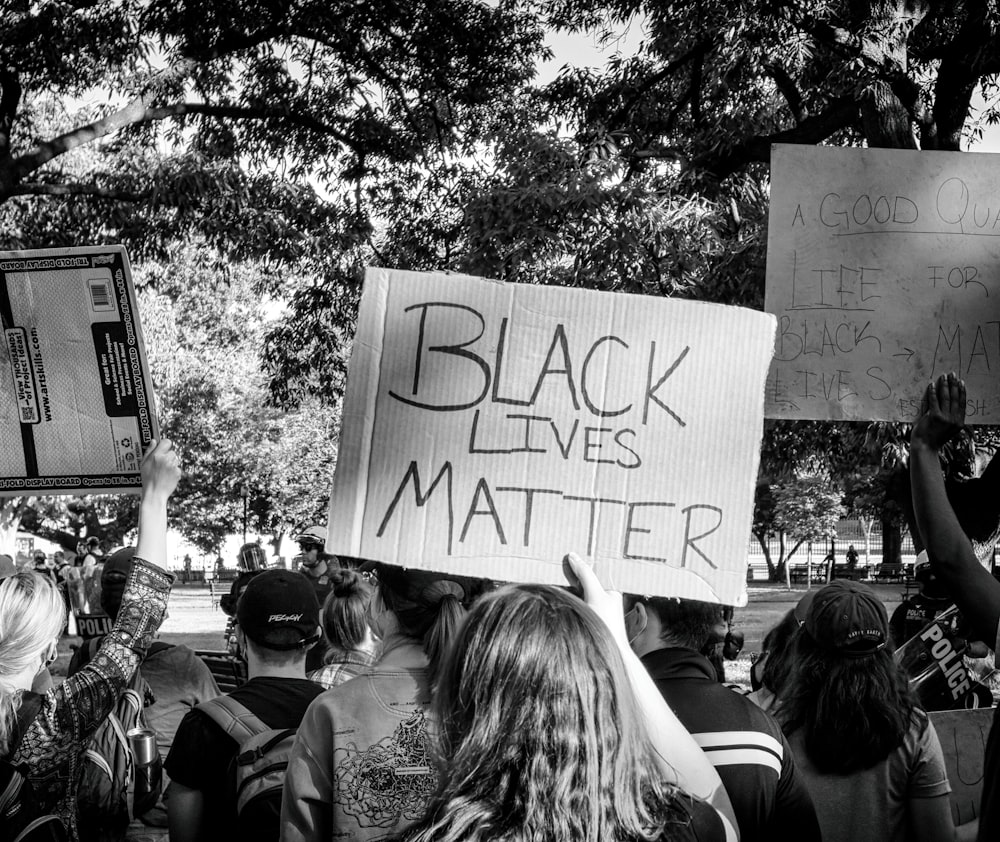 grayscale photo of people gathering near trees