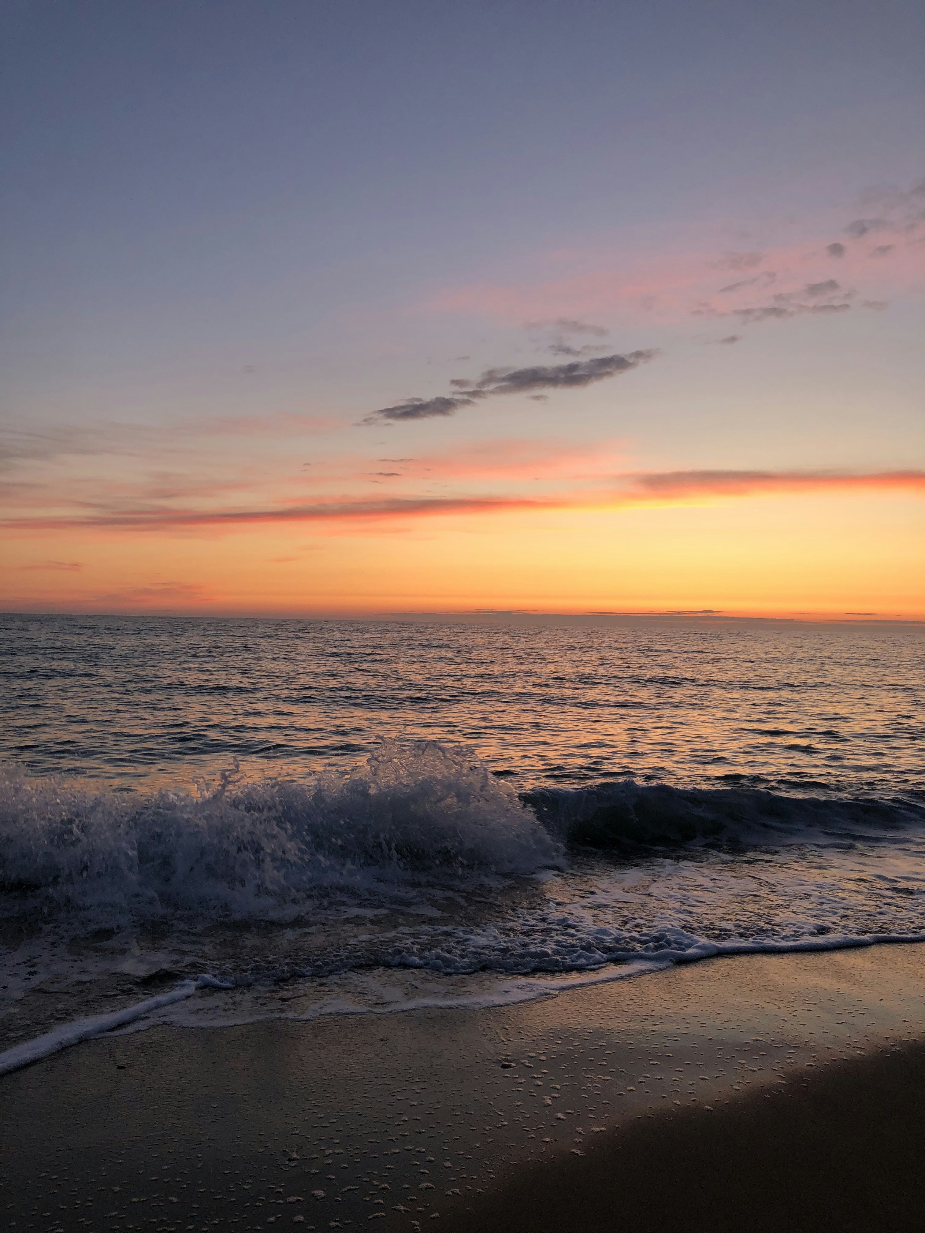 ocean waves crashing on shore during sunset