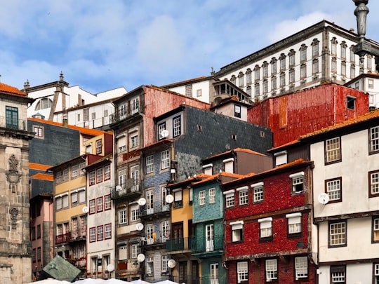 brown and green concrete buildings under blue sky during daytime in Ribeira Square Portugal