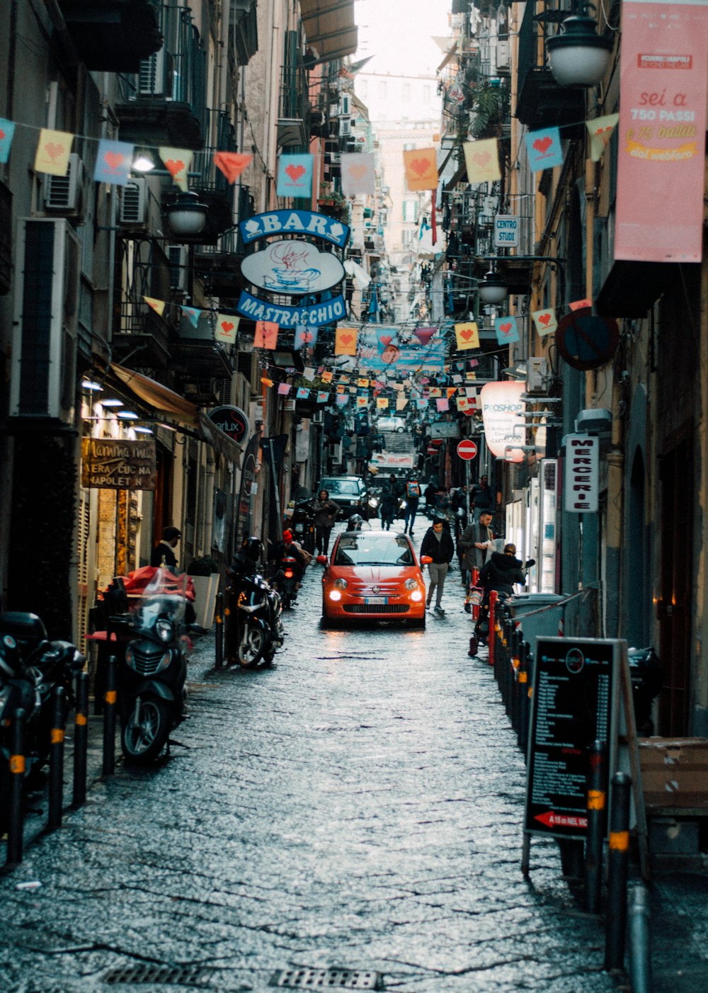 red car on road between buildings during daytime