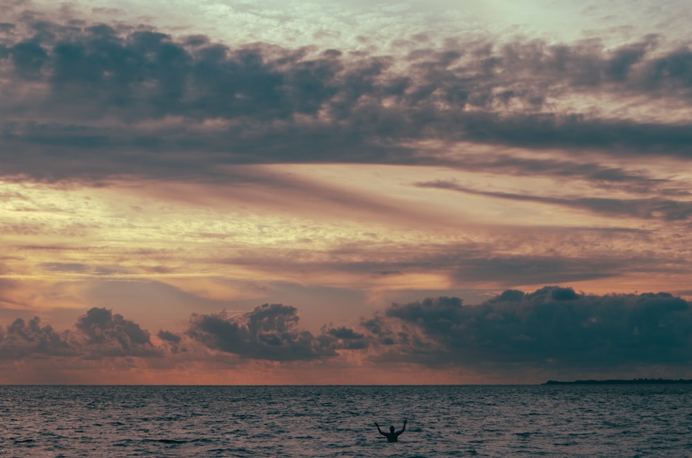 silhouette of person riding on boat on sea during sunset