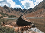 A serene moment of a person meditating by a calm lake surrounded by mountains.