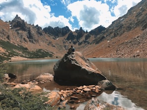 A serene moment of a person meditating by a calm lake surrounded by mountains.