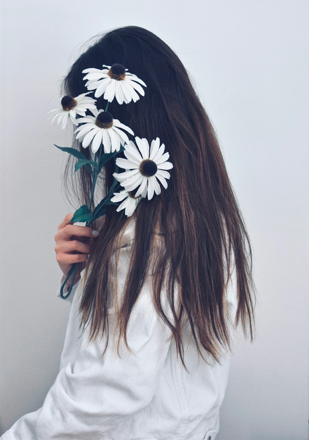 woman in white long sleeve shirt holding white and black flower
