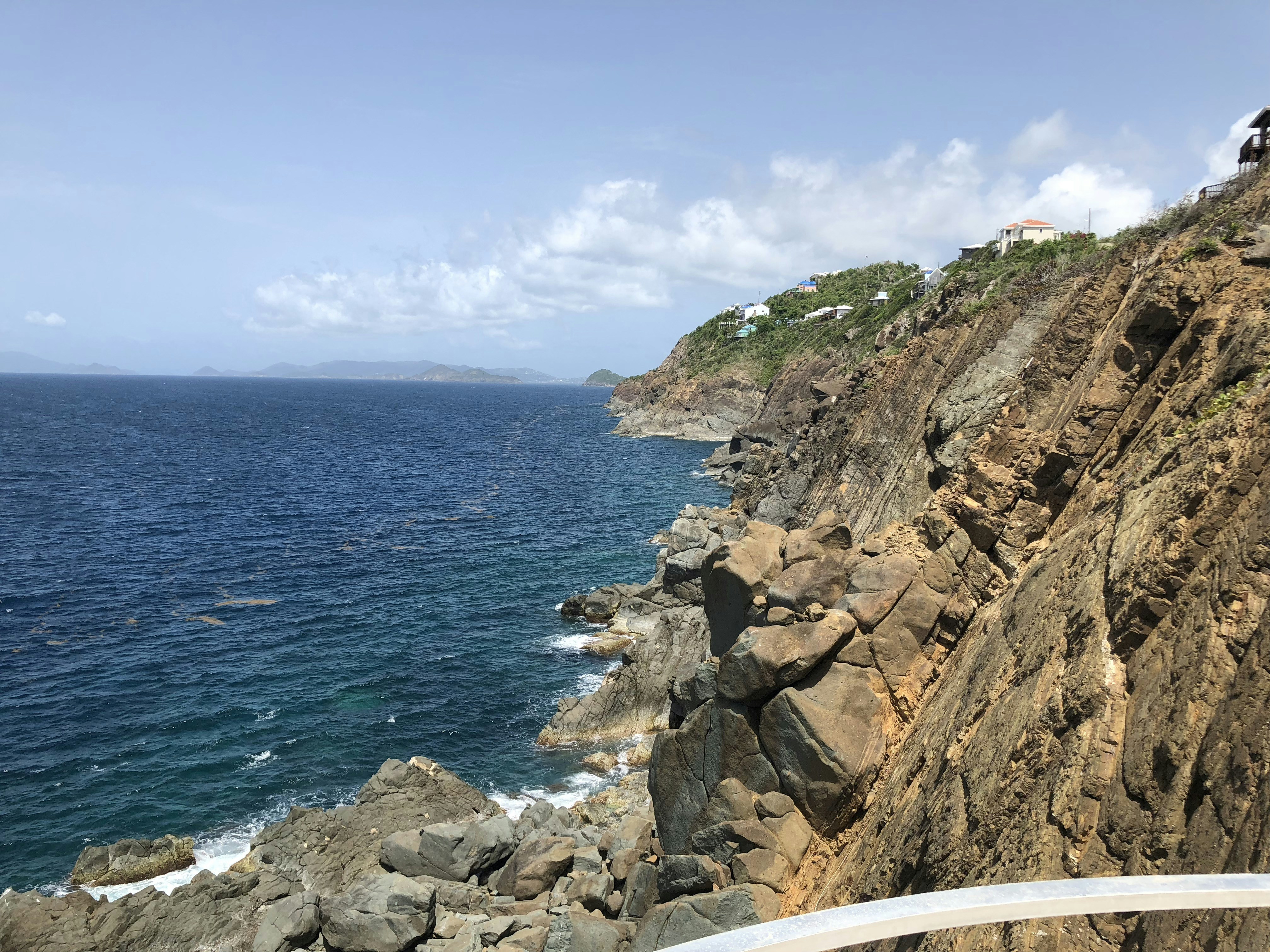 brown rocky mountain beside sea under blue sky during daytime