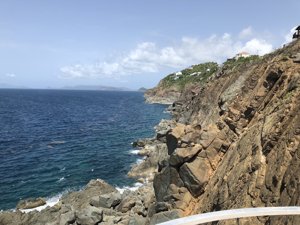 Brauner felsiger Berg am Meer unter blauem Himmel tagsüber