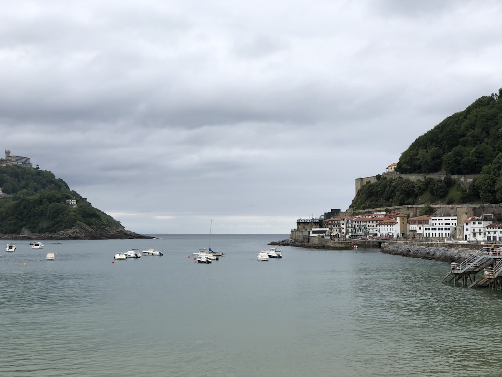 white boat on sea near green mountain under white clouds during daytime