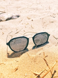 A pair of black sunglasses resting on a beach towel.