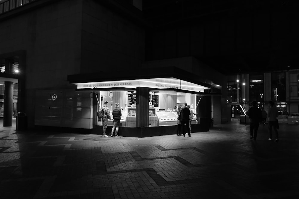 grayscale photo of people walking in front of store