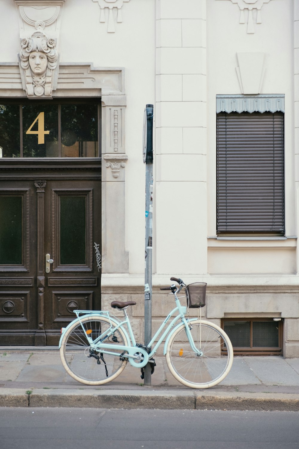Bicicleta urbana azul estacionada junto a la puerta de madera negra