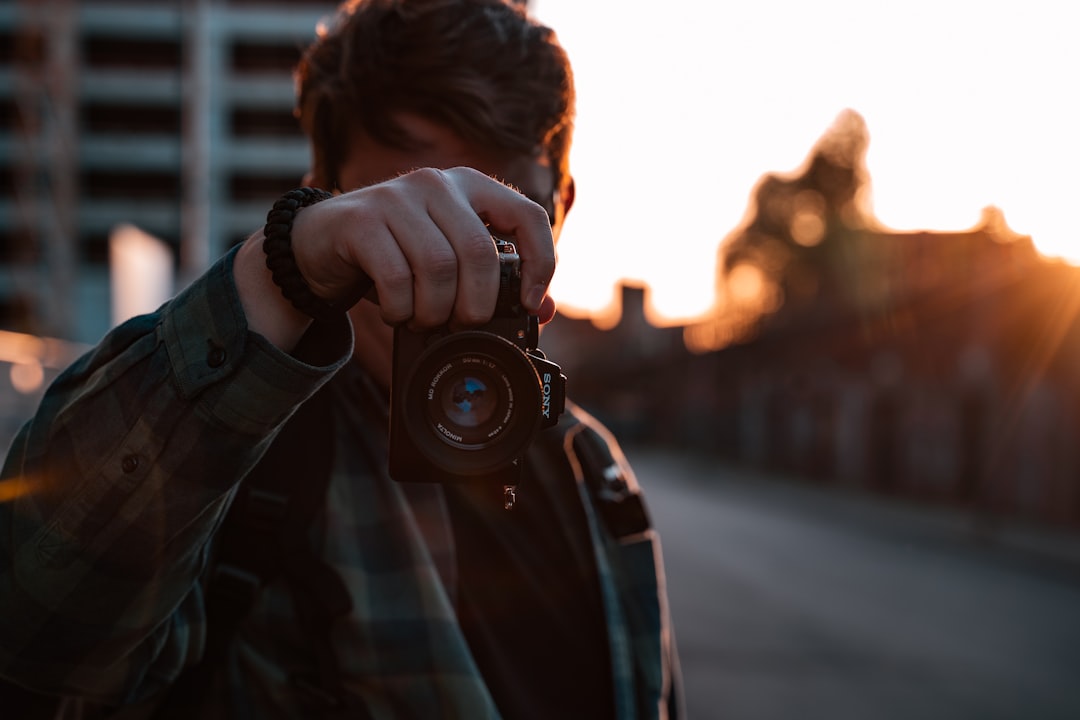 man in black and white plaid shirt holding black dslr camera