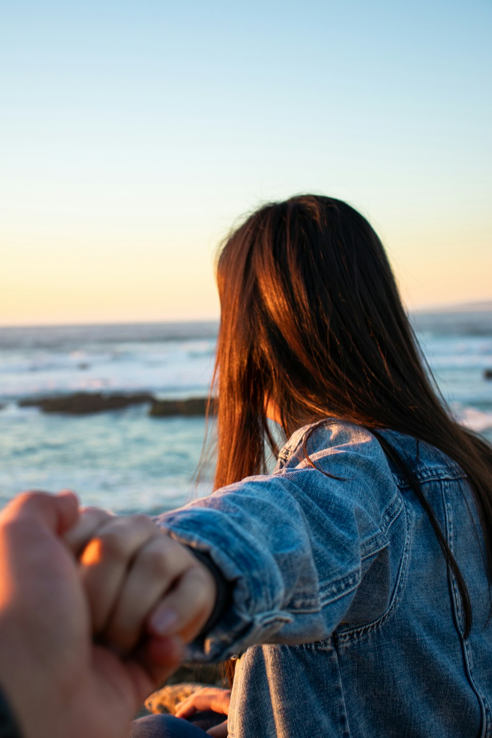 woman in blue denim jacket near sea during daytime