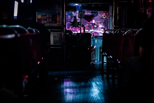 A vibrant party bus interior lit with colorful lights and plush seating.