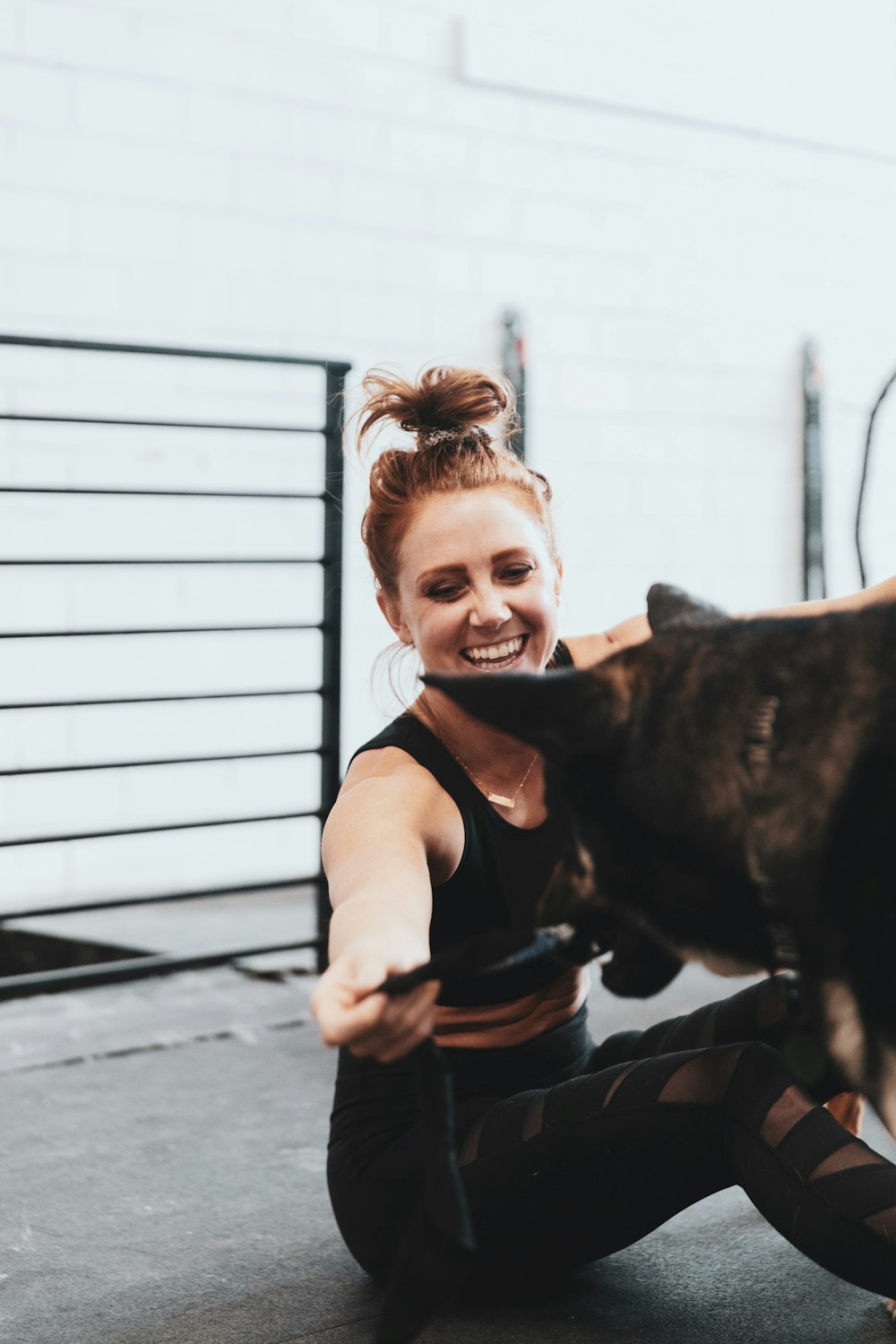 girl in pink t-shirt hugging black short coated dog