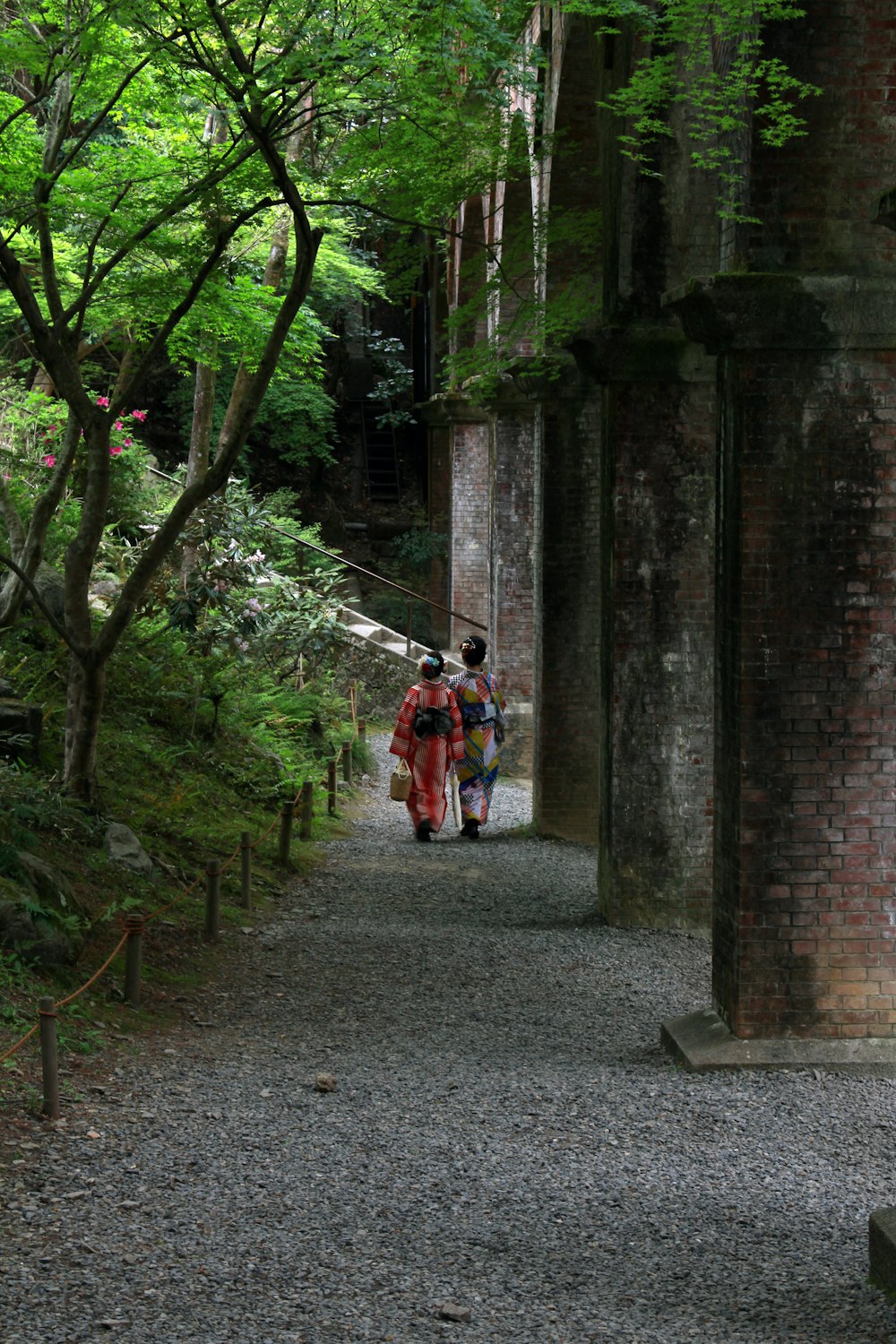 3 men in red jacket walking on gray asphalt road during daytime