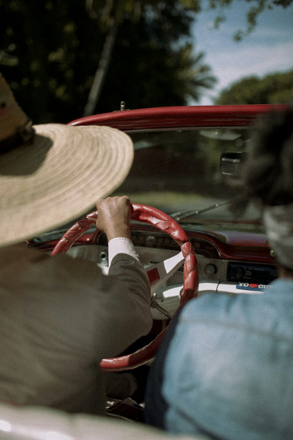 man in white long sleeve shirt and brown hat sitting on car seat