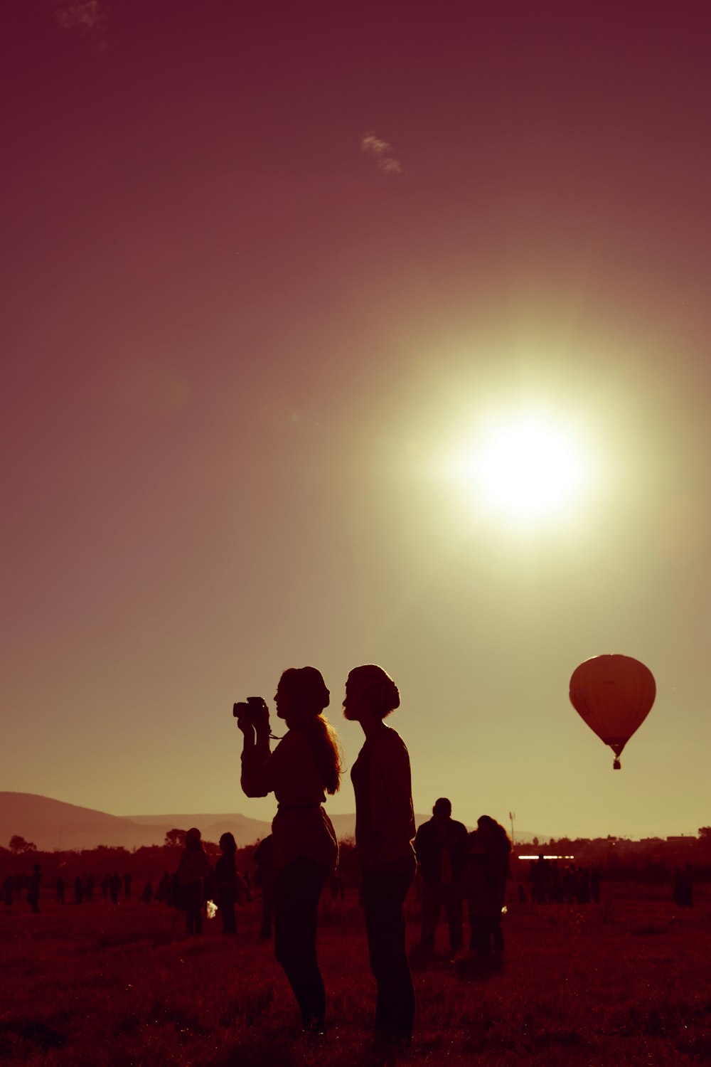 silhouette of people standing and sitting on ground during sunset