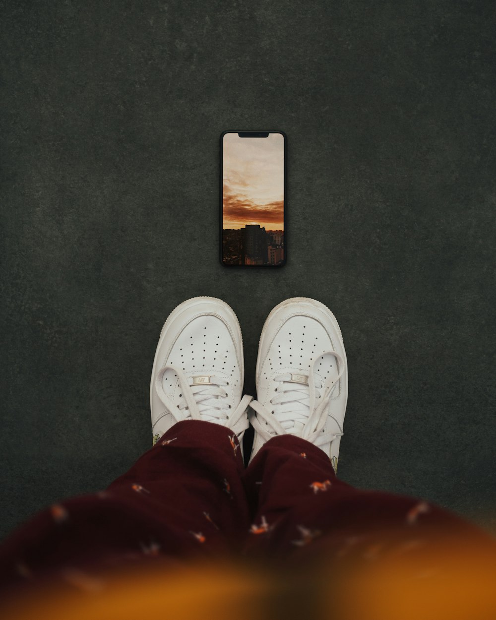 person wearing white sneakers standing on gray floor