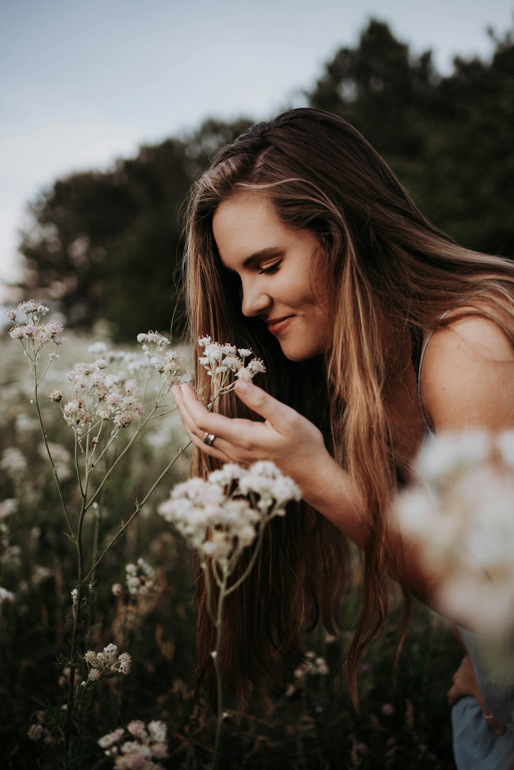 mulher no topo branco sem mangas segurando flores brancas