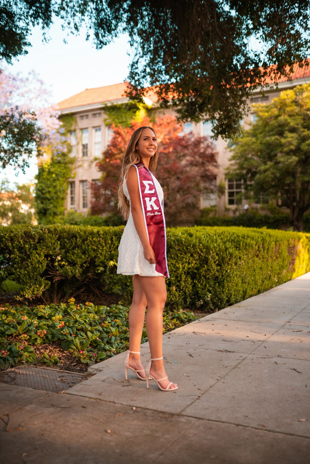 woman in white and red long sleeve dress standing on gray concrete pathway during daytime