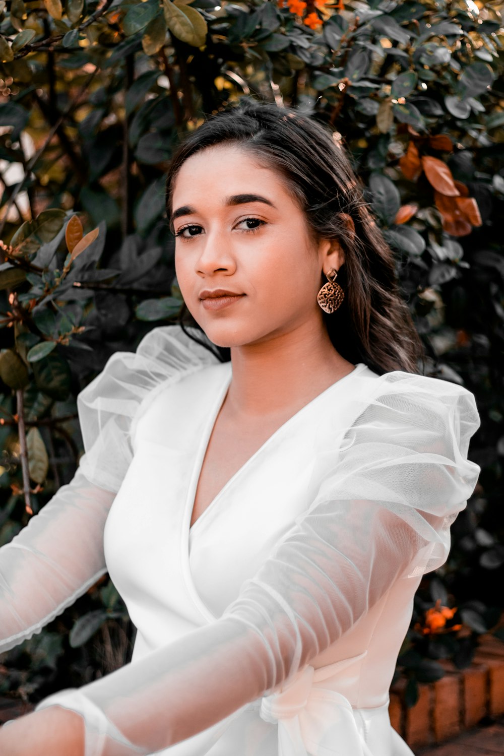 woman in white long sleeve shirt standing near brown leaves