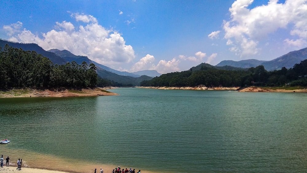 people swimming on sea near mountain under blue sky during daytime