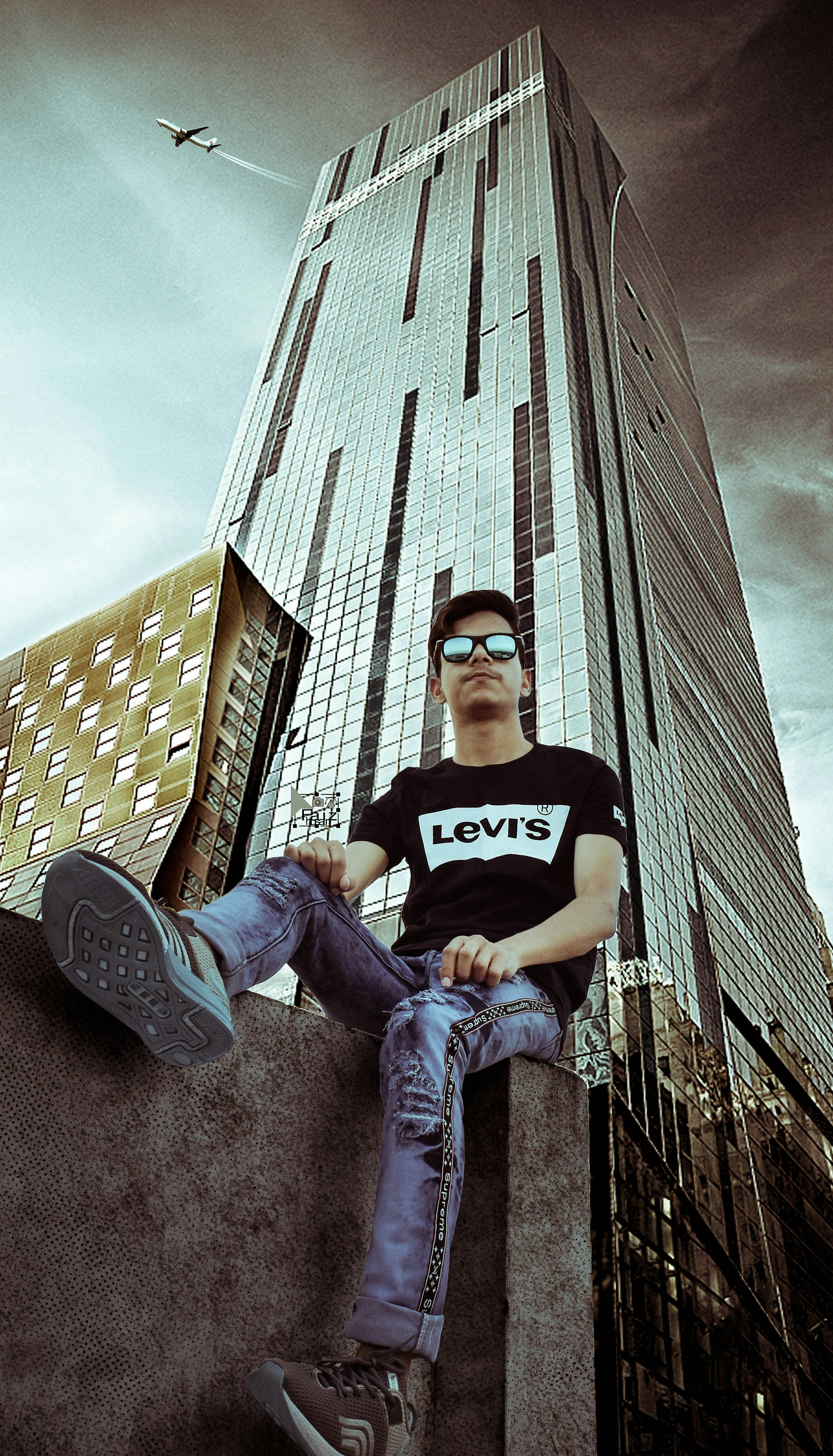 man in black crew neck t-shirt and blue denim jeans sitting on brown concrete building