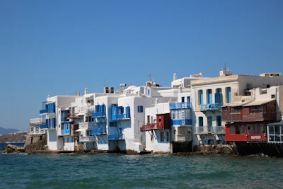 White and blue medina walls of Asilah stretching along the Atlantic Ocean coastline in bright sunlight.