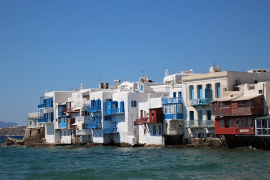 white and red concrete building beside body of water during daytime in Little Venice Greece