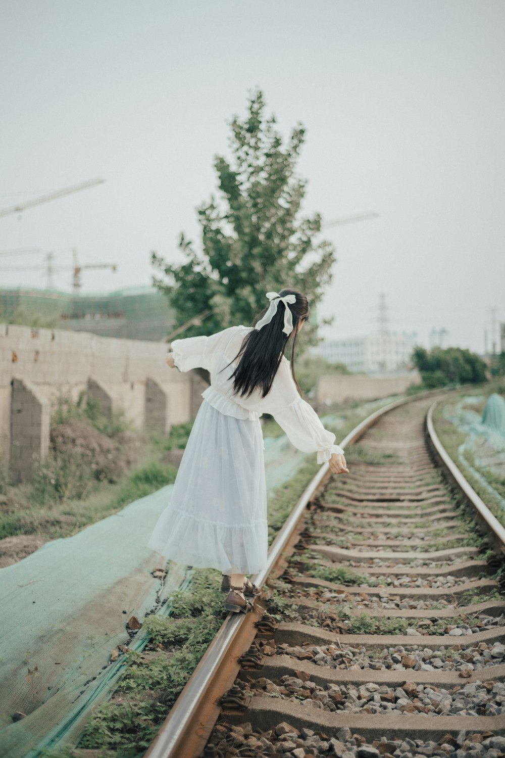 woman in white wedding dress walking on train rail during daytime