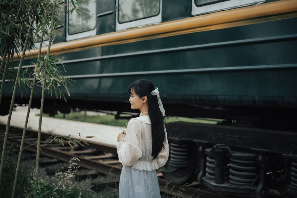 girl in white dress standing beside train during daytime