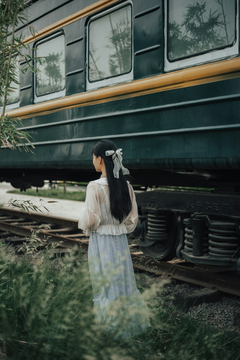 woman in white long sleeve shirt and white skirt standing on train rail during daytime