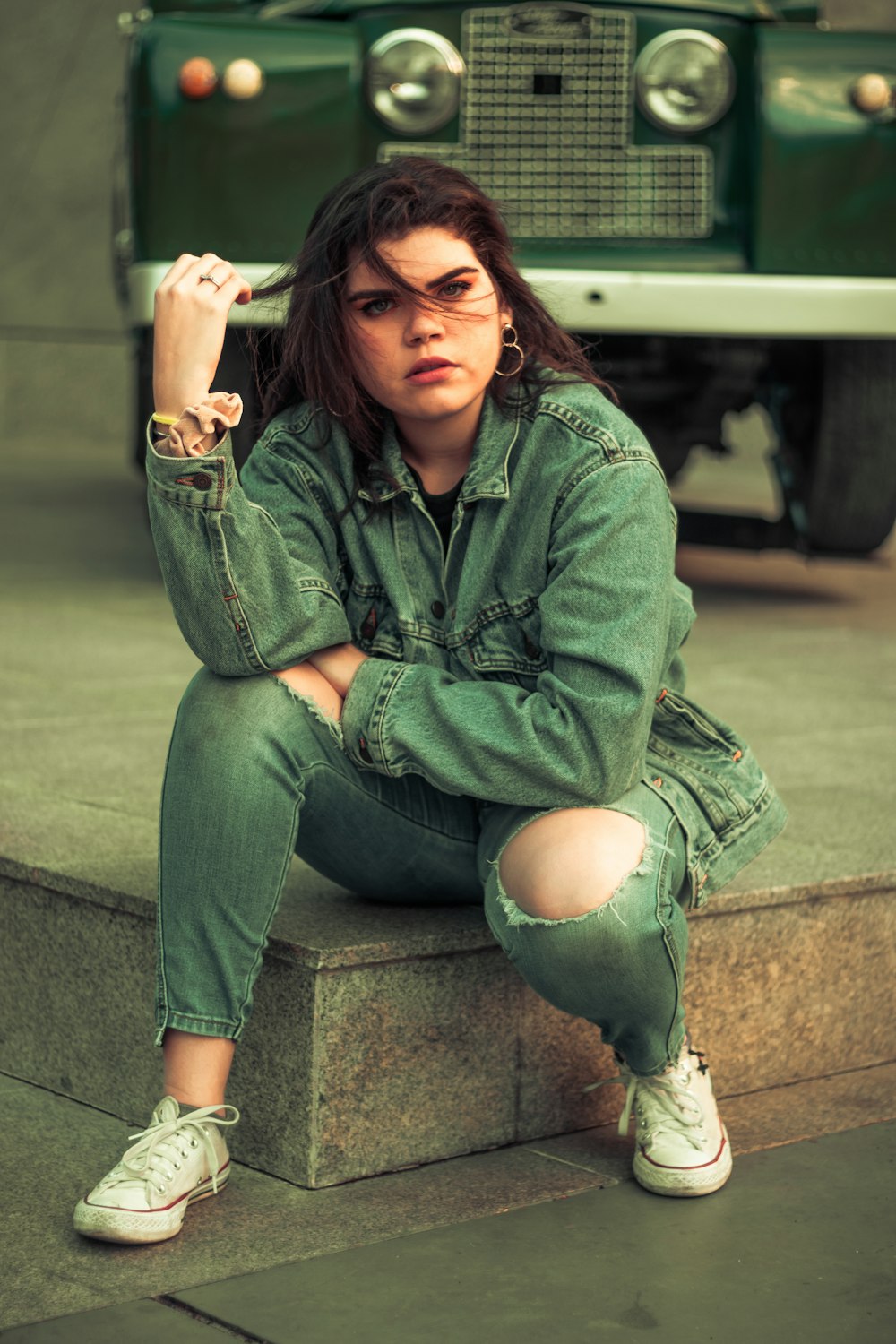 woman in blue denim jacket and blue denim jeans sitting on concrete bench during daytime